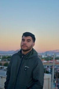 a man in a hoodie standing on a rooftop