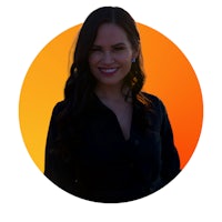 a woman in a black shirt smiling in front of an orange background